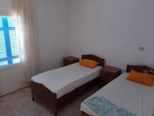 deux lits dans une chambre avec une fenêtre et un lit sidx sidx sidx dans l'établissement Appartement deux chambres-calme proche plage, à Ḩammām al Ghazzāz