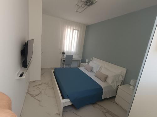 a white bedroom with a blue bed and a television at La casa di mest Pepp in Monopoli