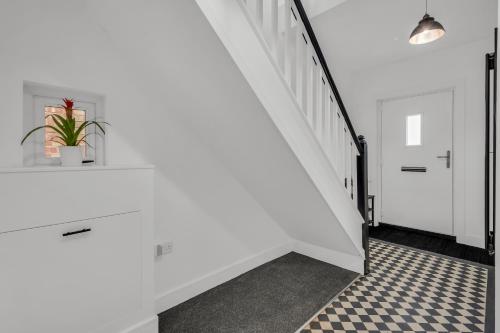 a hallway with white walls and a staircase with a potted plant at Stanley Park House Peterborough - 3 bed, 3 bathroom, parking, garden in Peterborough