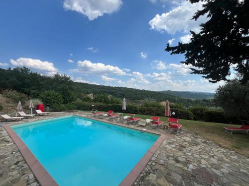a swimming pool with chairs and a view of the mountains at Il Fiorino di Badia in Badia A Passignano