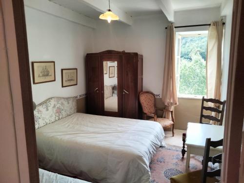 une chambre avec un lit, une chaise et une fenêtre dans l'établissement Agréable maison au centre de La Salvetat sur Agout, à La Salvetat-sur-Agout