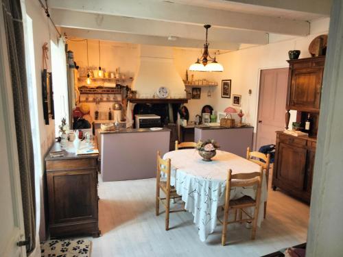 une cuisine avec une table et des chaises dans une pièce dans l'établissement Agréable maison au centre de La Salvetat sur Agout, à La Salvetat-sur-Agout