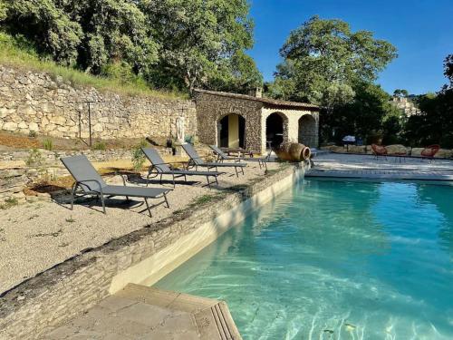 une piscine avec des chaises longues à côté d'un bâtiment dans l'établissement Mas Sylios, à Le Beaucet