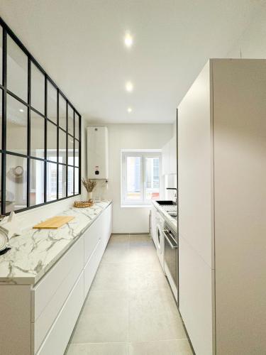 une cuisine avec des placards blancs et une grande fenêtre dans l'établissement La Cigale - Centre Ville - Wifi, à Cassis