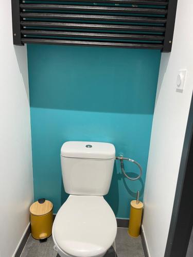a bathroom with a white toilet in a blue wall at L'Oasis Ensoleillée - Jardin-Terrasse- 5 min plage in Montjoly