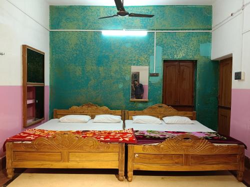 a bedroom with two beds and a ceiling fan at Virat Palace in Deoghar