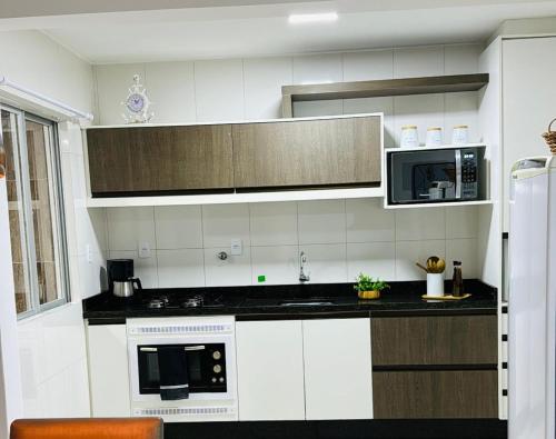 a kitchen with white cabinets and a black counter top at Apartamento Mar grosso 100 metros do MAR in Laguna