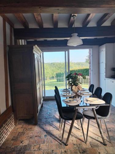 une salle à manger avec une table et des chaises et une grande fenêtre dans l'établissement Le gite des pommiers, à Haudricourt