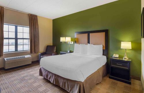 a hotel room with a large bed and a chair at Extended Stay America Suites - Chicago - Elmhurst - O'Hare in Elmhurst