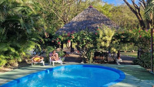 a woman sitting in a chair next to a swimming pool at Villasjungle 2 in Sámara