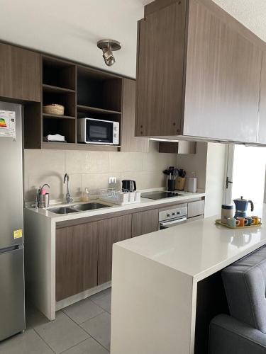 a kitchen with wooden cabinets and a white counter top at Kennedy Premium Apartments Colorado in Santiago