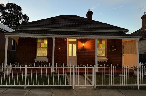 a house with a white fence in front of it at Cottage on Manilla - Bathurst - Centrally located in Bathurst