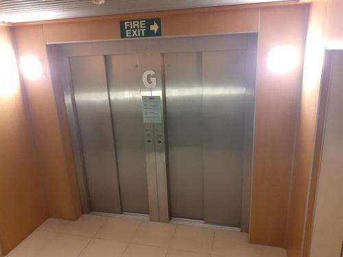 an elevator in a building with a fire exit sign on it at Esplanade Apartments in Whitianga