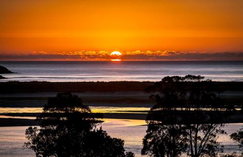 a sunset over the ocean with the sun setting at A Cova Do Traski in Ponteceso