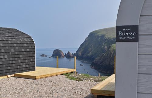 a building with a wooden deck with a view of the ocean at SEApods - Isle of Lewis - Luxury en-suite pods on the edge of the Atlantic Ocean in Aird Uig