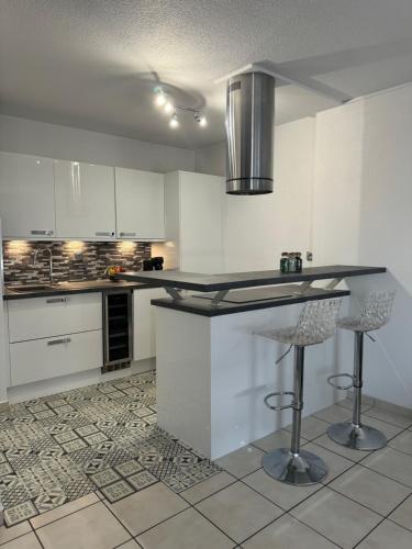 une cuisine avec un comptoir et deux tabourets de bar dans l'établissement Appartement avec piscine sur le toit, à Villeurbanne