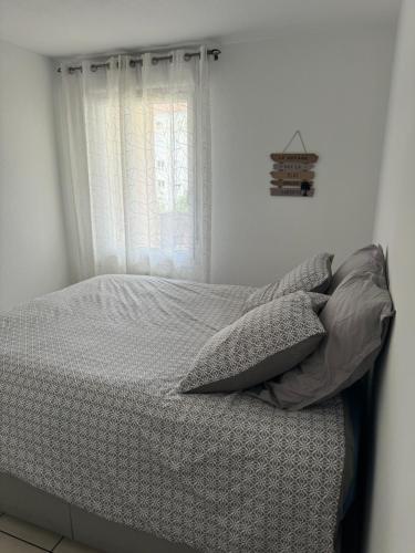 une chambre avec un lit avec des oreillers et une fenêtre dans l'établissement Appartement avec piscine sur le toit, à Villeurbanne
