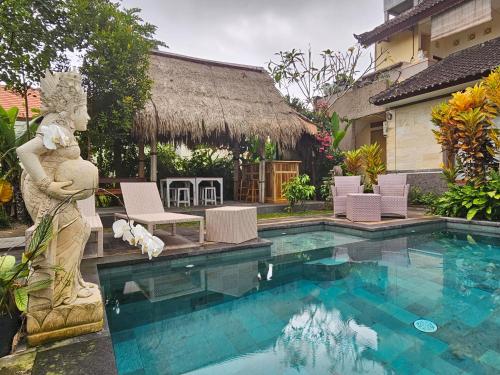 a swimming pool with a statue next to a house at Dukuh Village Villas & Art in Tegalalang