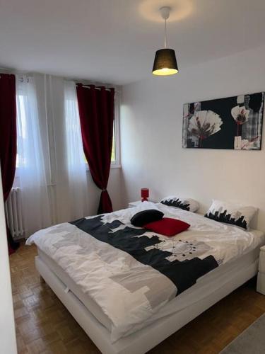 une chambre avec un grand lit blanc avec des oreillers rouges dans l'établissement Charmant T2 à Maisons Alfort - Tout meublé neuf, à Maisons-Alfort