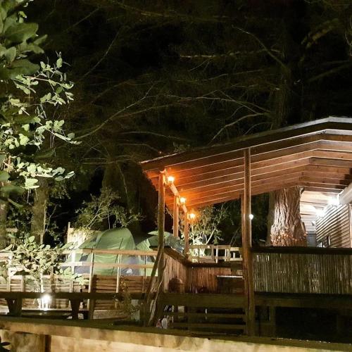a wooden pavilion with a table and a tree at night at Glamping Puertecillo Surf & Camp in Puertecillo