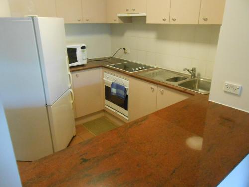 a kitchen with a white refrigerator and a sink at City Plaza in Canberra