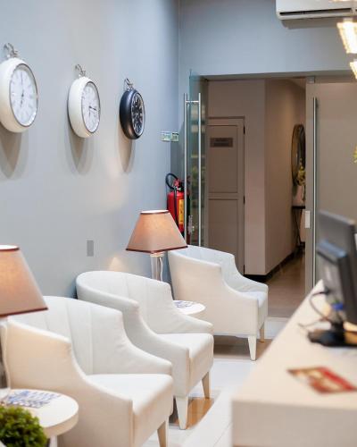 a waiting room with white chairs and clocks on the wall at FAIAS - Boutique Hotel in Luanda