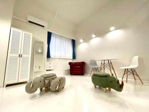 a room with three stuffed elephants and a red chair at 彩光堂Village KAME101&202 in Tokyo