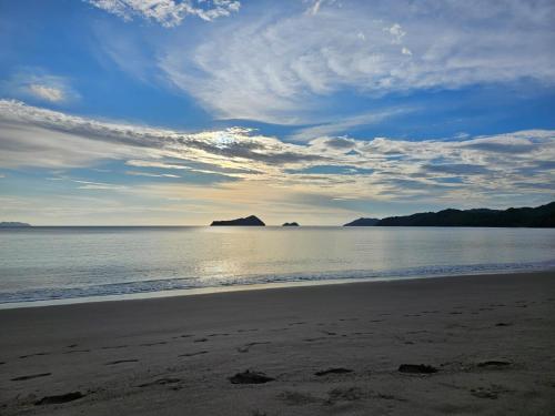 a beach with a cloudy sky and the ocean at Casona Cocobolo el mejor lugar de Costa Rica in Guanacaste