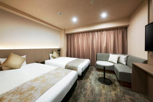 a hotel room with two beds and a couch at Hotel Villa Fontaine Tokyo-Kayabacho in Tokyo
