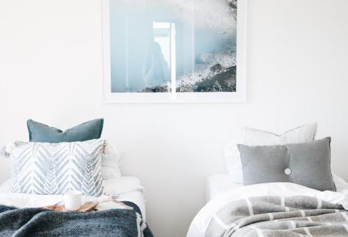 a bedroom with two beds and a picture on the wall at Villas Waiheke in Onetangi