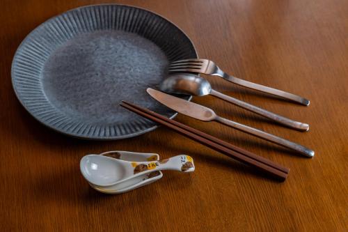 a wooden table with a plate and utensils on it at ねこ蔵の宿 飛騨 in Hida
