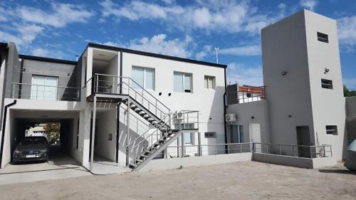 a white house with a car parked in the driveway at Heart Depto 2 Viedma Centro Confortable y Optima Ubicación in Viedma