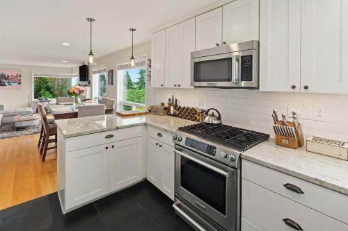 a kitchen with white cabinets and a stove top oven at Blue Oasis with Amazing Olympic Views in Seattle