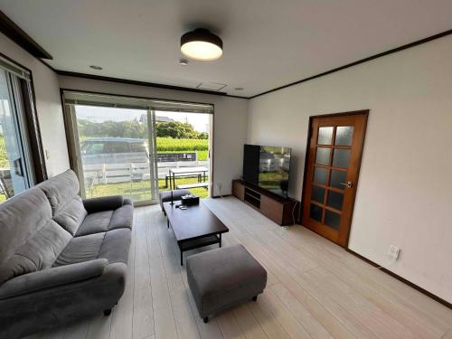 a living room with a couch and a flat screen tv at ダイヤモンドヘッドいすみ in Chōjamachi