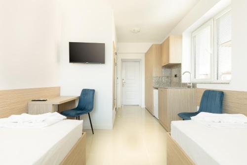 two beds in a room with a desk and a kitchen at Millennia Hotel in Sofia
