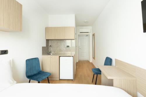 a bedroom with a bed and a kitchen with blue chairs at Millennia Hotel in Sofia