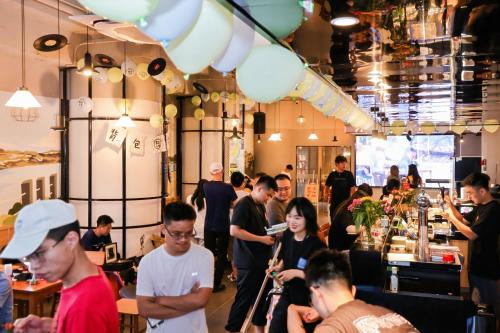 a group of people standing around a bar in a restaurant at Xiamen Desti Youth Park Hostel Zhongshan Road in Xiamen