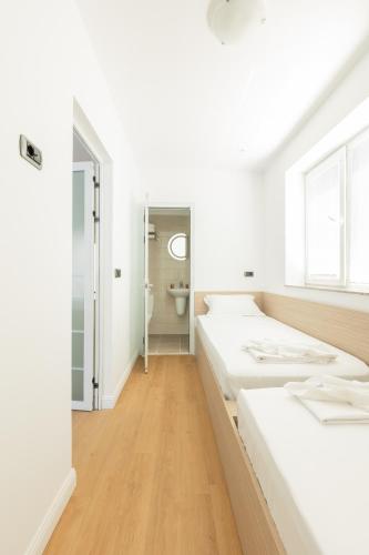 a white room with two beds and a toilet at Millennia Hotel in Sofia