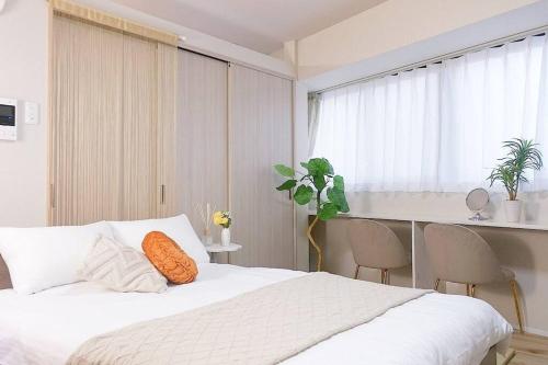 a bedroom with a white bed with an orange pillow at USJまで2駅5分,最上階701 Residential Hotel Alex - 西九条駅から徒歩4分の好立地 in Osaka