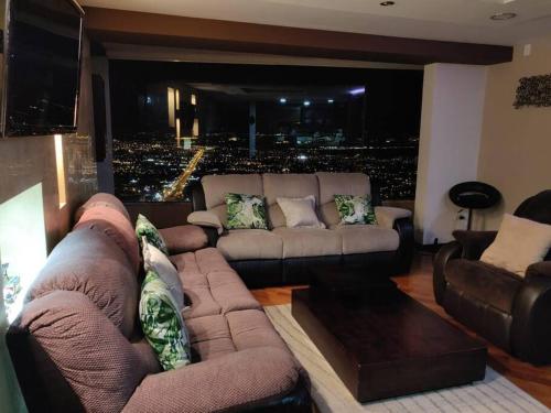 a large living room with a couch and a large city at Vista Real Modern View Jacuzzi hidromasaje in Quito