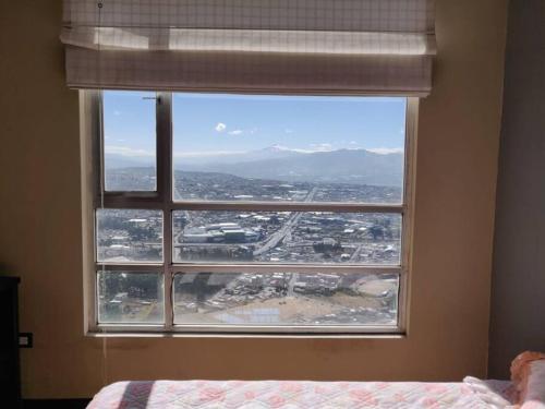 a bedroom window with a view of a city at Vista Real Modern View Jacuzzi hidromasaje in Quito