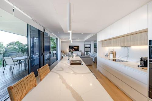 a kitchen and living room with a table and chairs at The Hamptons Lake House - Noosa Heads Luxury House in Noosa Heads