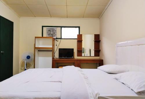 a bedroom with a bed and a desk and a window at Hotel Grand Astoeti in Kopo 2