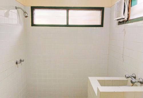 a white bathroom with a sink and a window at Hotel Grand Astoeti in Kopo 2