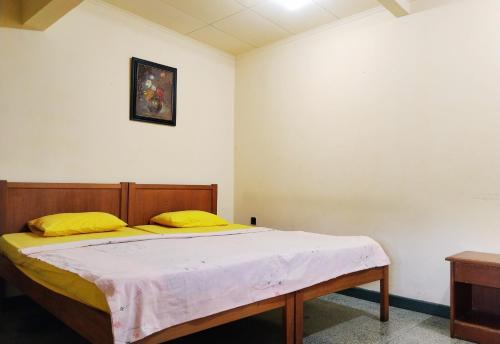 a bedroom with a large bed with yellow pillows at Hotel Grand Astoeti in Kopo 2
