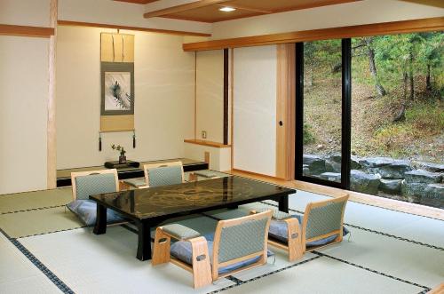 a dining room with a glass table and chairs at Yamagamionsen Yunomotokan in Toki