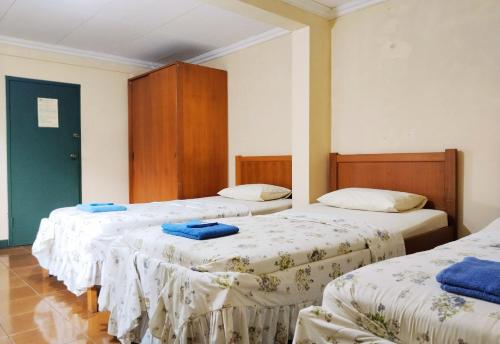 a room with three beds with blue towels on them at Hotel Grand Astoeti in Kopo 2