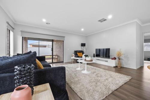 a living room with a blue couch and a tv at The Alfredton - Spacious Ballarat Stay for Families in Alfredton