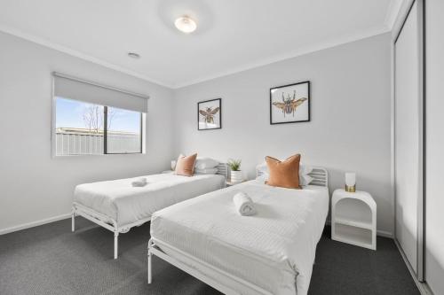 a white bedroom with two beds and a window at The Alfredton - Spacious Ballarat Stay for Families in Alfredton
