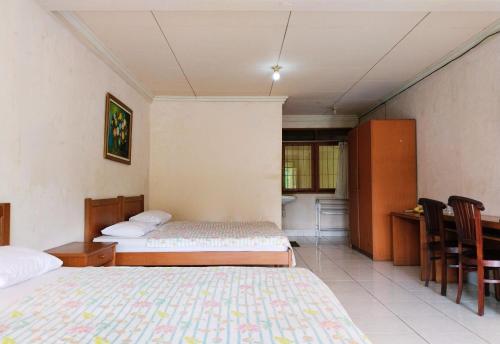 a room with two beds and a table and chairs at Hotel Grand Astoeti in Kopo 2